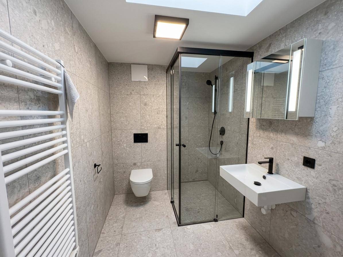 Modernes Badezimmer mit großformatigen Fliesen, ebenerdiger Dusche und beheiztem Handtuchhalter.