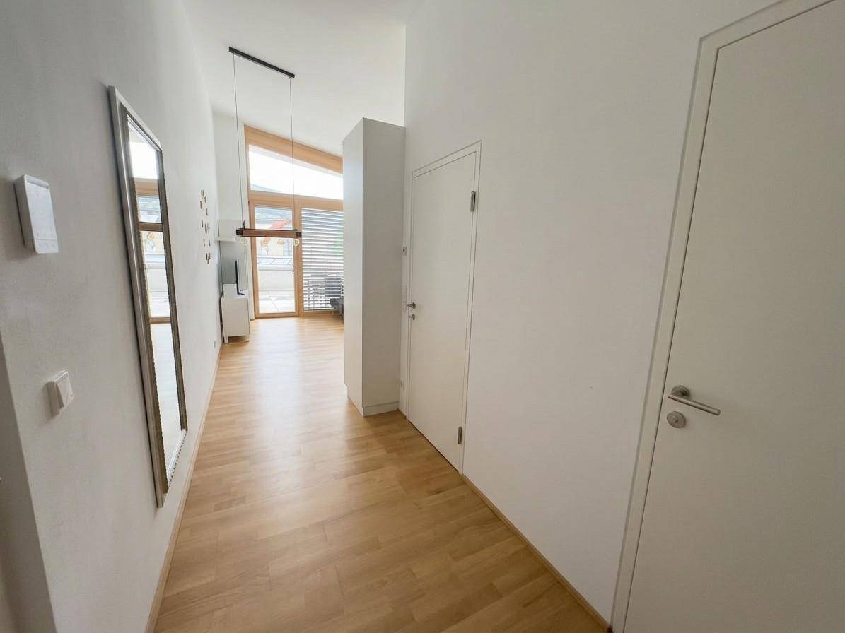 Heller Flur mit Holzboden, großem Spiegel und Zugang zu weiteren Räumen.