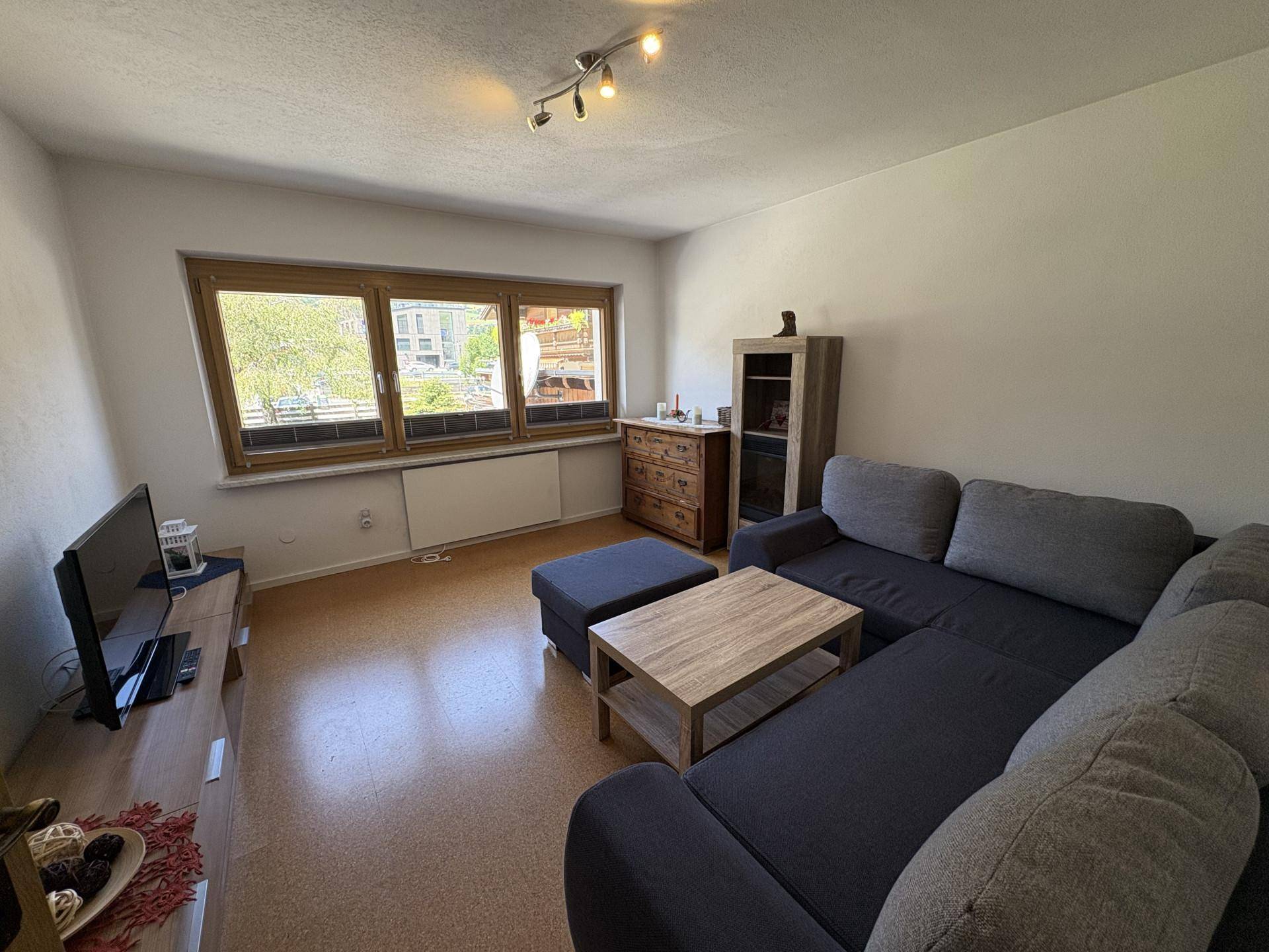 Gemütliches Wohnzimmer mit großem Ecksofa, Holztisch und natürlichem Lichteinfall durch das Fenster.