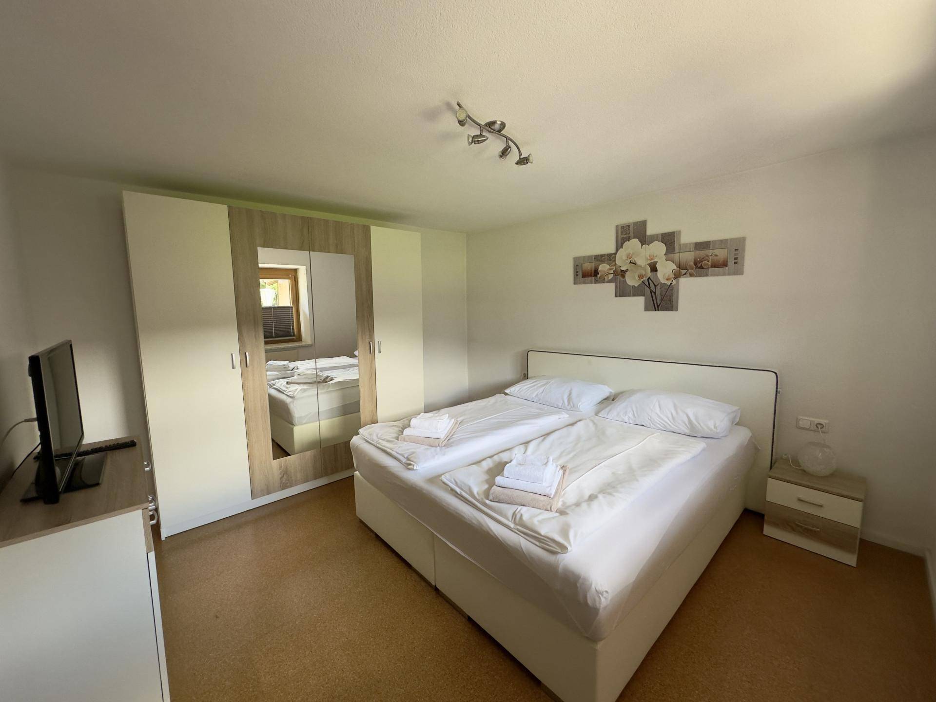 Helles Schlafzimmer mit komfortablem Doppelbett und praktischem Kleiderschrank mit Spiegelfront.