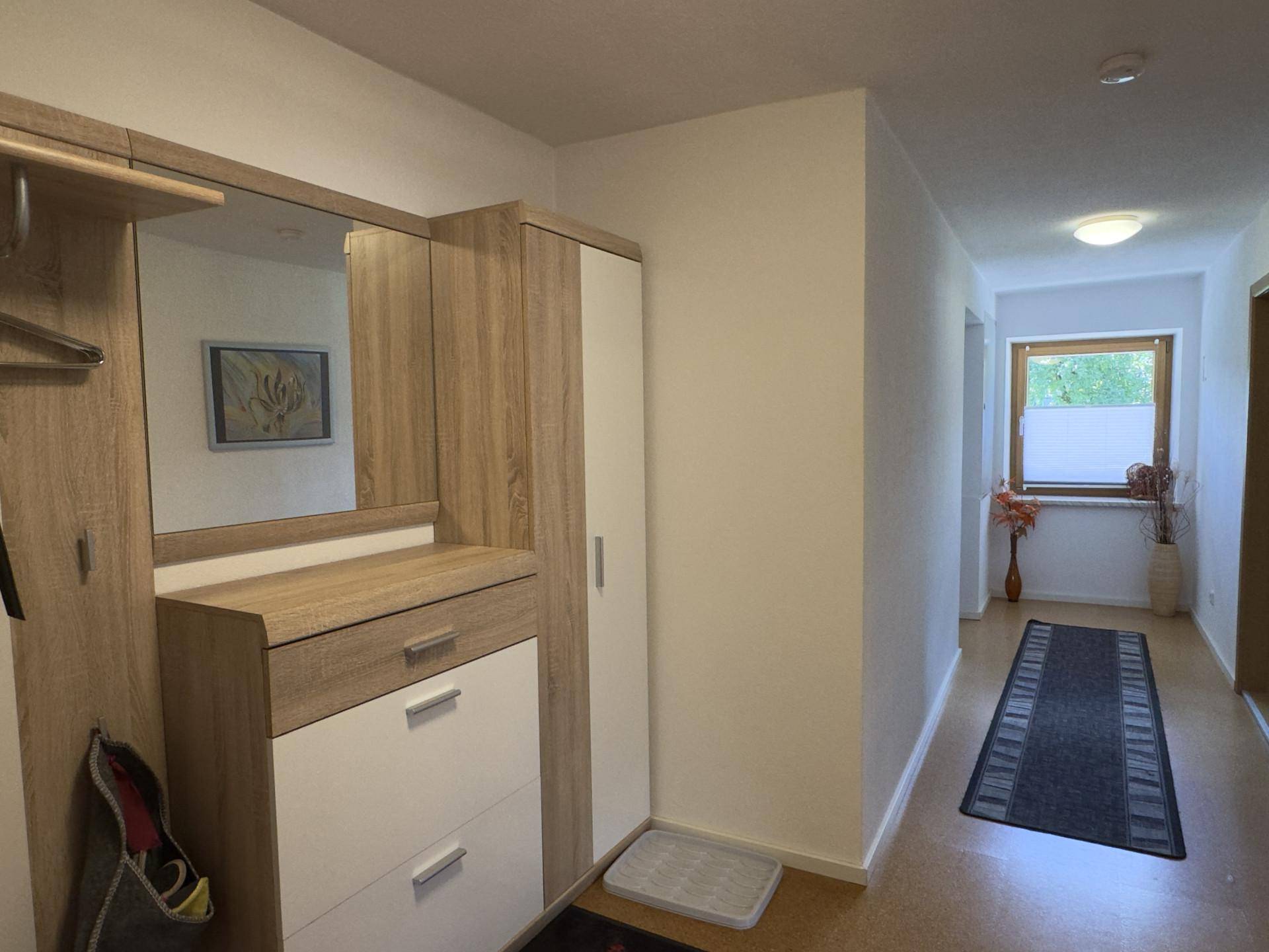 Eingangsbereich mit Garderobe, Spiegel und einem Fenster, das für natürliches Licht sorgt.