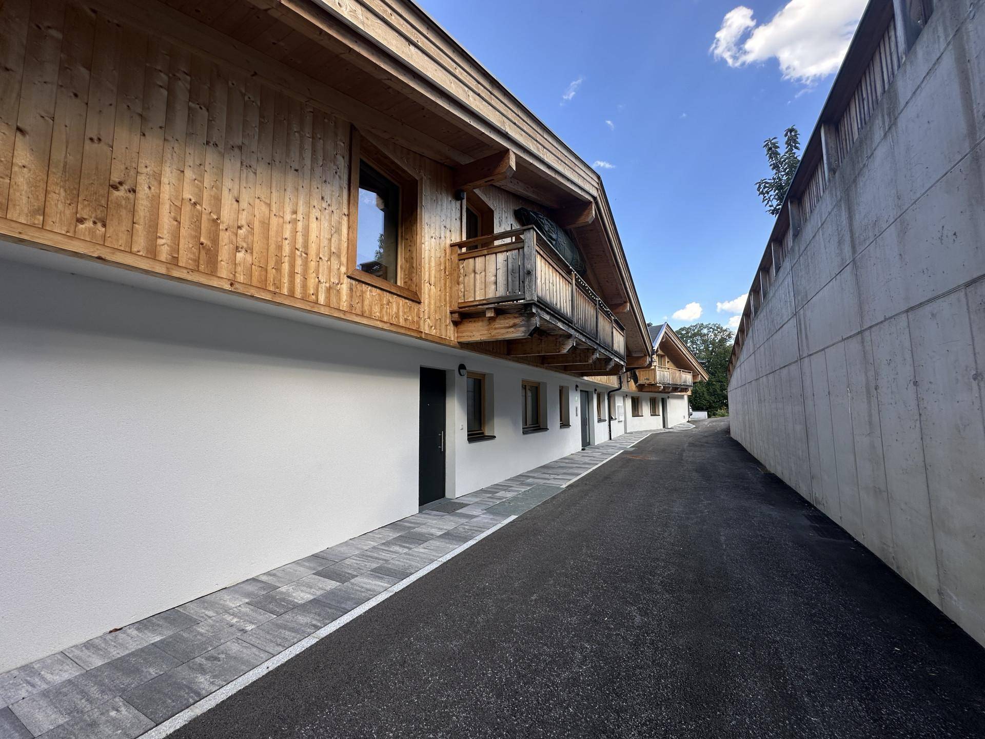 Moderne Architektur mit Holzfassade und Balkonen entlang einer Zufahrtsstraße.