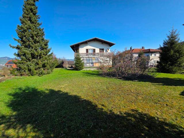 Weitläufige Rasenfläche des Gartens mit Blick auf das Wohnhaus und die umliegende Landschaft.