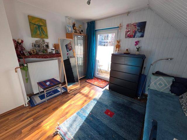 Helles Schlafzimmer mit Holzboden, Zugang zum Balkon und Dachschräge.