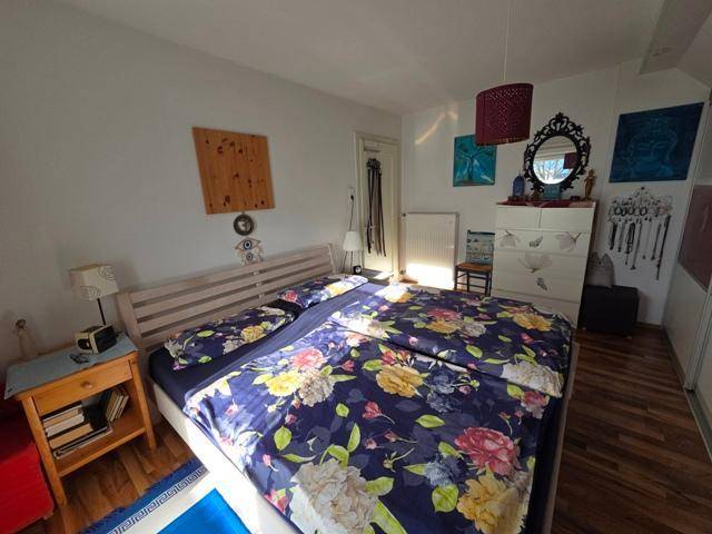 Gemütliches Schlafzimmer mit Doppelbett, Holzboden und farbenfroher Bettwäsche.