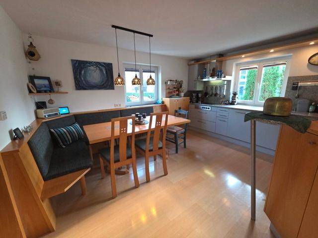 Geräumige Wohnküche mit integriertem Essbereich, Holzboden und modernen Küchengeräten.