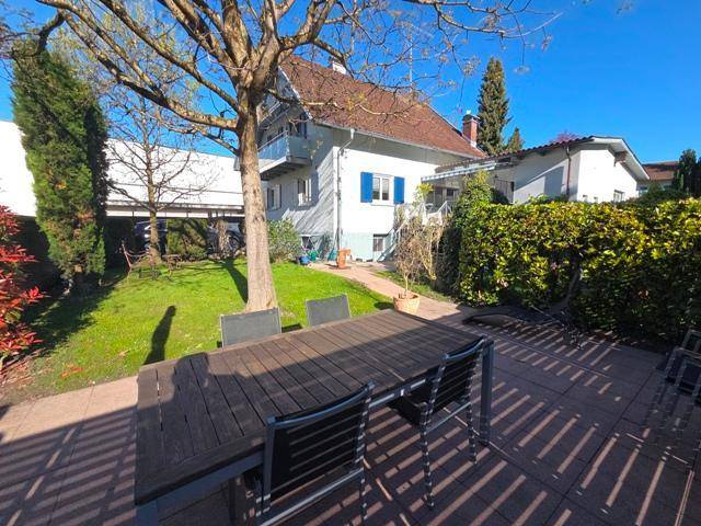 Große gepflasterte Terrasse mit Esstisch und Stühlen im Gartenbereich des Hauses.