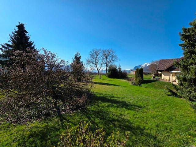 Weitläufige Rasenfläche des Gartens mit Bäumen und Blick auf die umliegende Landschaft und Berge.