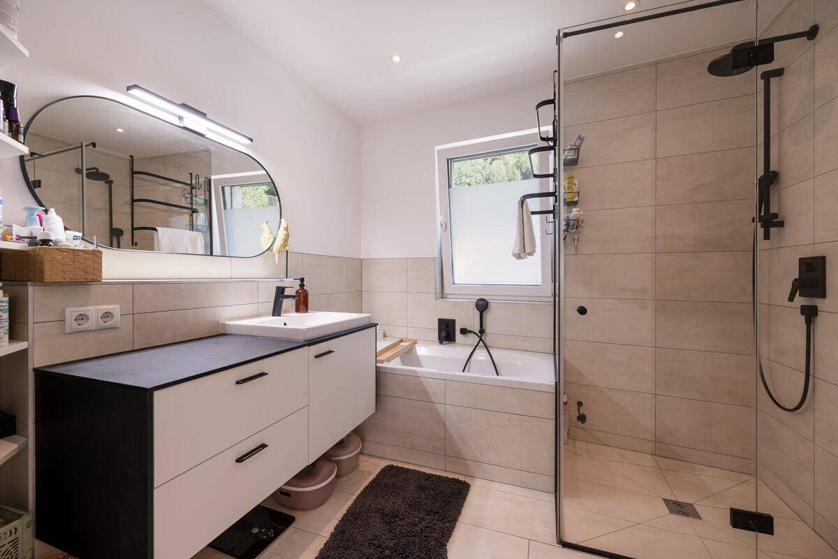 Modernes Badezimmer mit begehbarer Dusche, Badewanne, Einzelwaschbecken und Fenster.