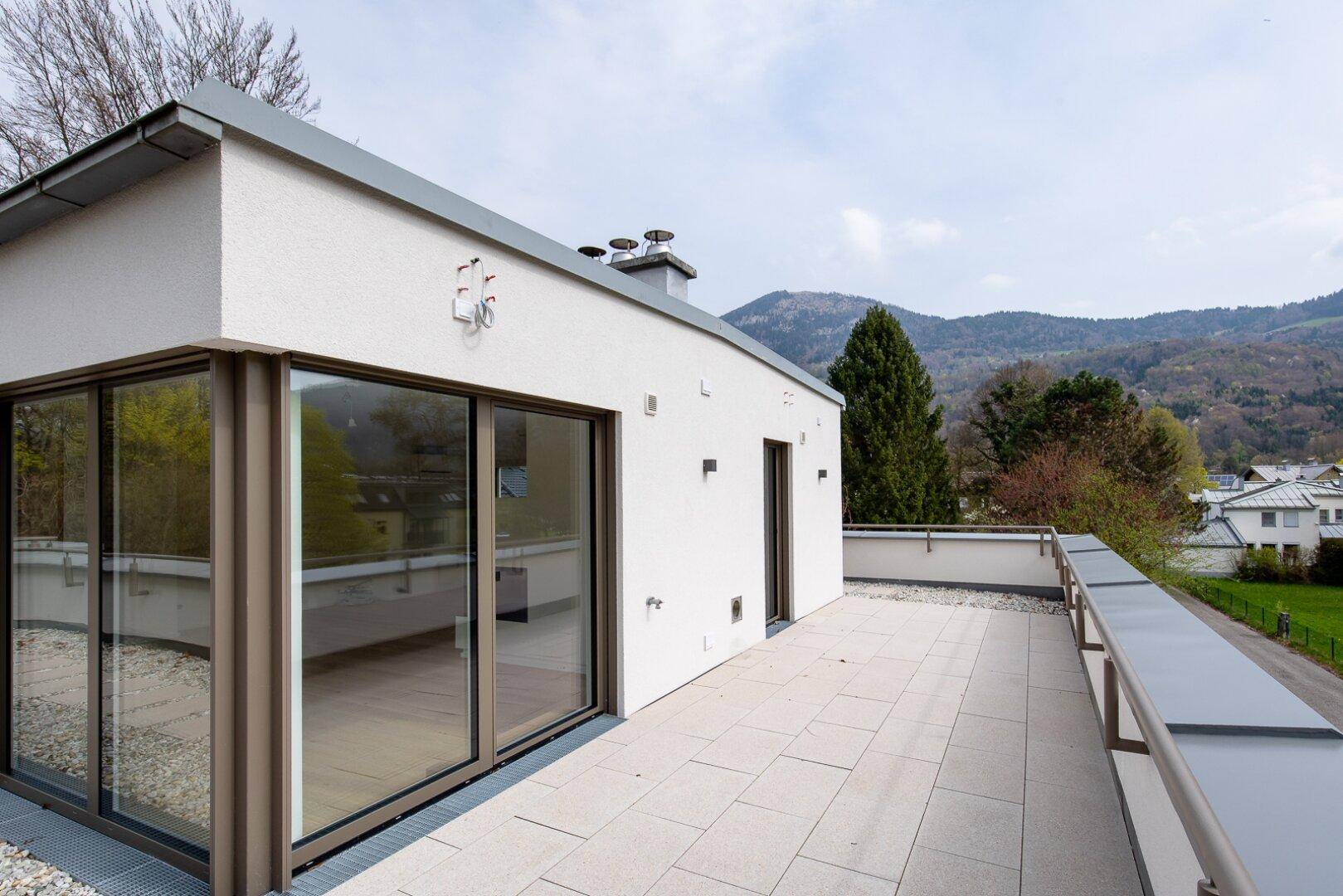 Große Dachterrasse mit moderner Architektur und weitem Blick auf die Berge.