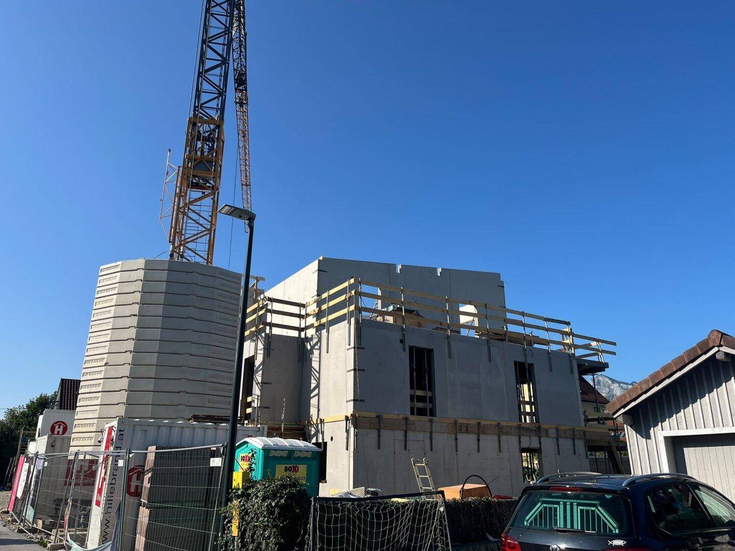 Baustelle eines neuen Gebäudes mit sichtbarer Betonkonstruktion und Kran im Hintergrund.