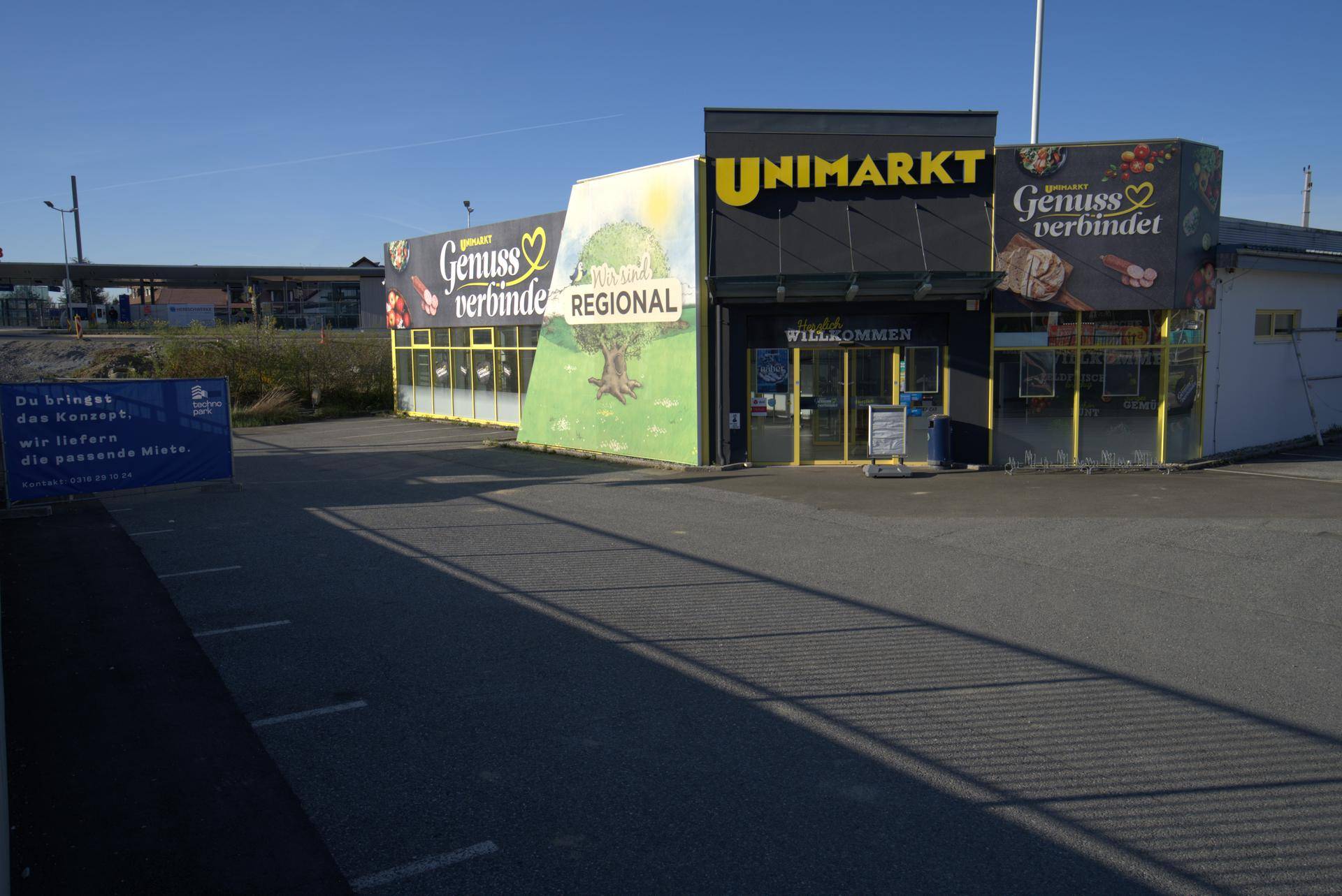 Vorderansicht des Supermarktes mit Werbeflächen und einem Teil des Parkplatzes.
