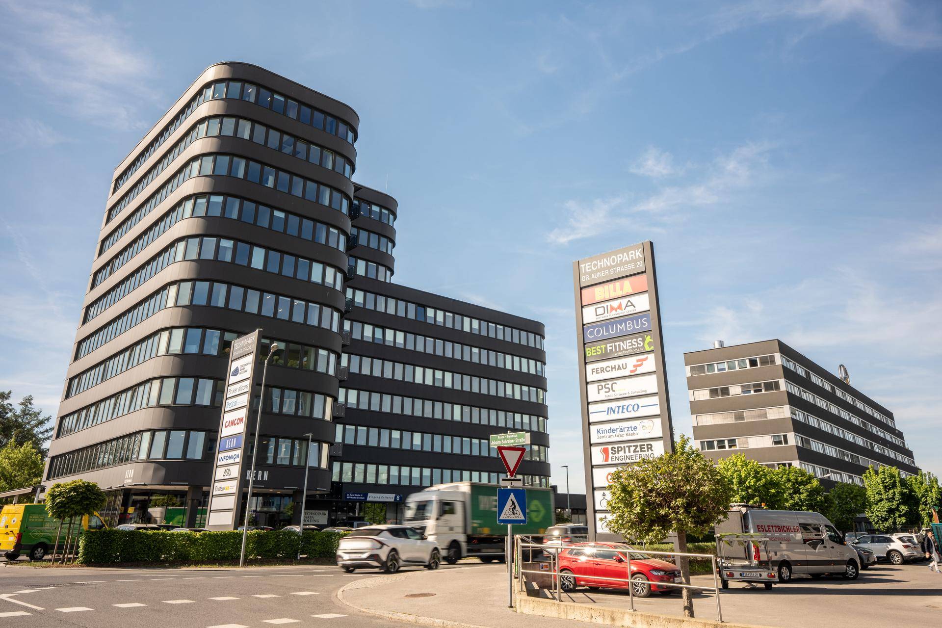 Ansicht des modernen Bürokomplexes mit geschwungener Architektur und umliegenden Parkplätzen.