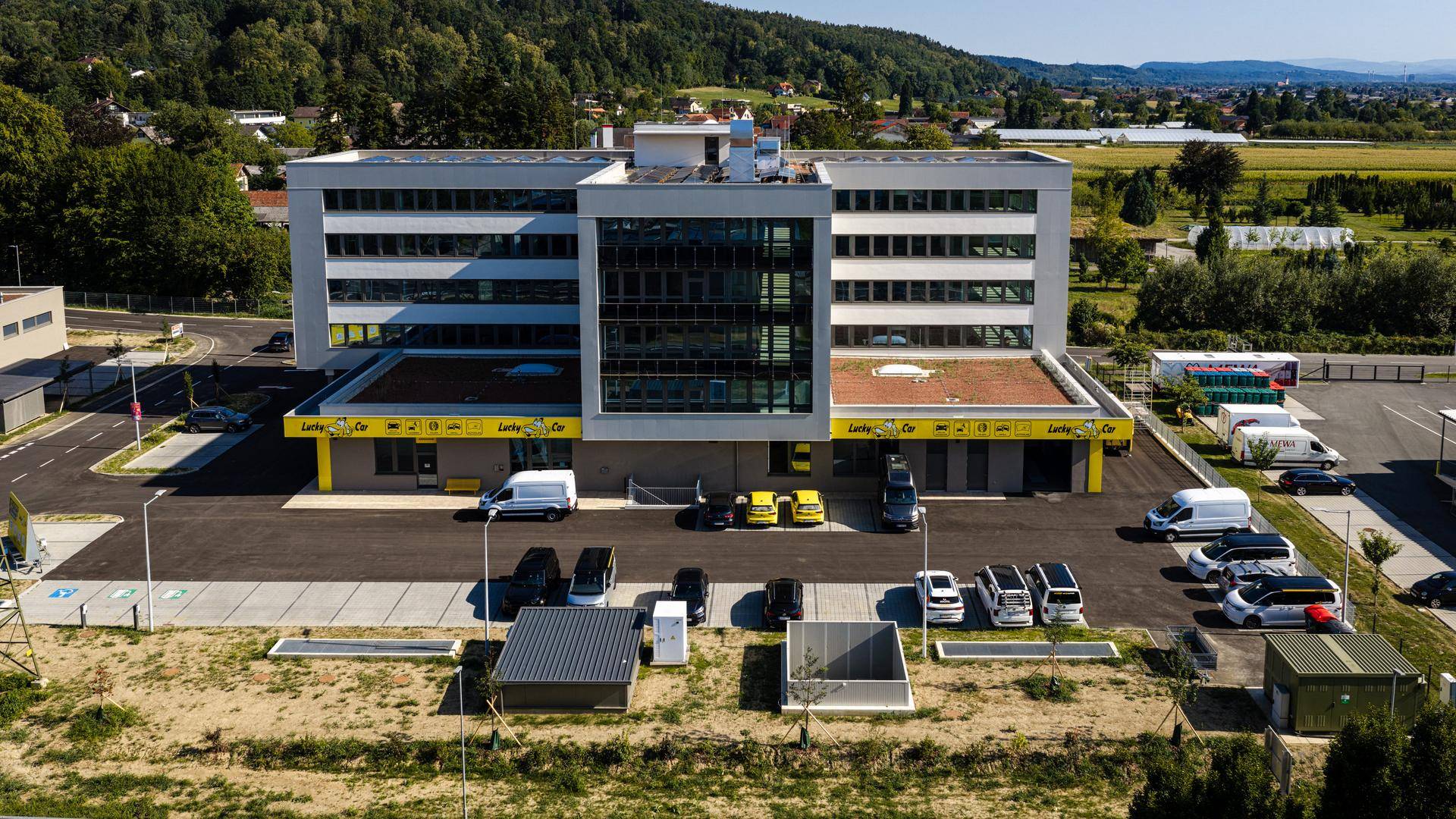 Ansicht eines modernen Geschäftsgebäudes mit großen Fensterfronten und Kundenparkplätzen.