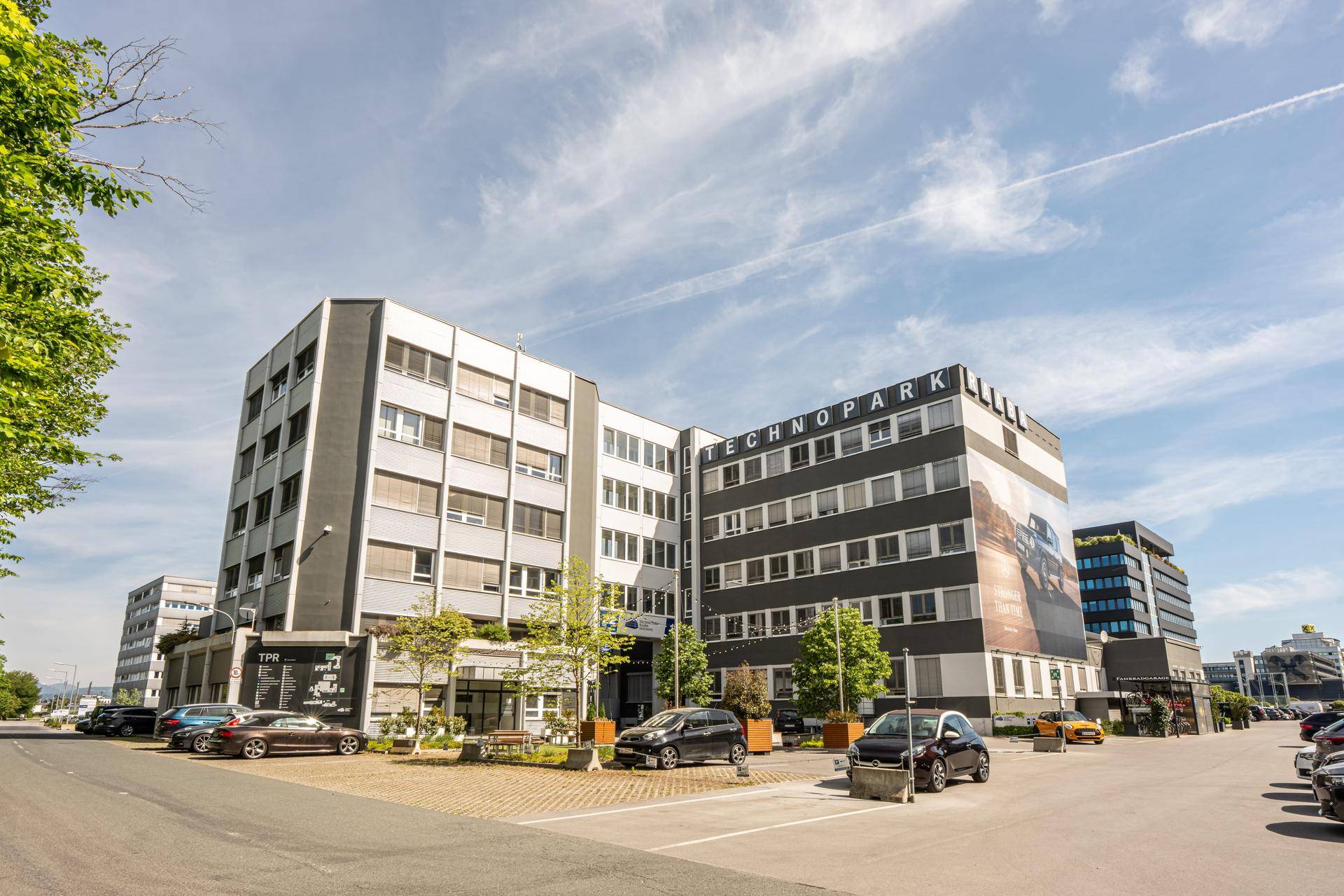 Modernes Bürogebäude des Technoparks mit großen Fenstern und einem prominenten Schriftzug unter blauem Himmel.