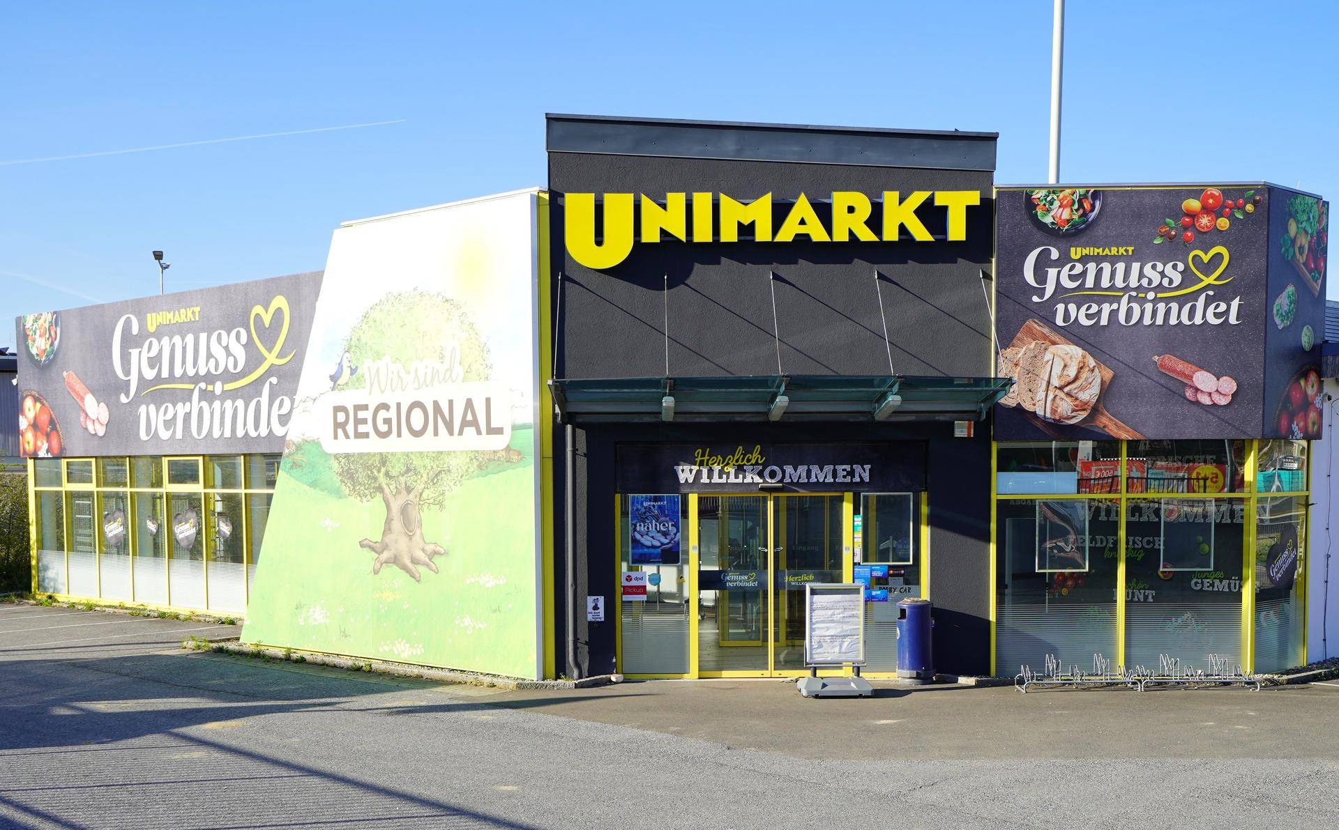 Eingangsbereich des Supermarktes Unimarkt mit Werbeschildern und automatischen Türen.