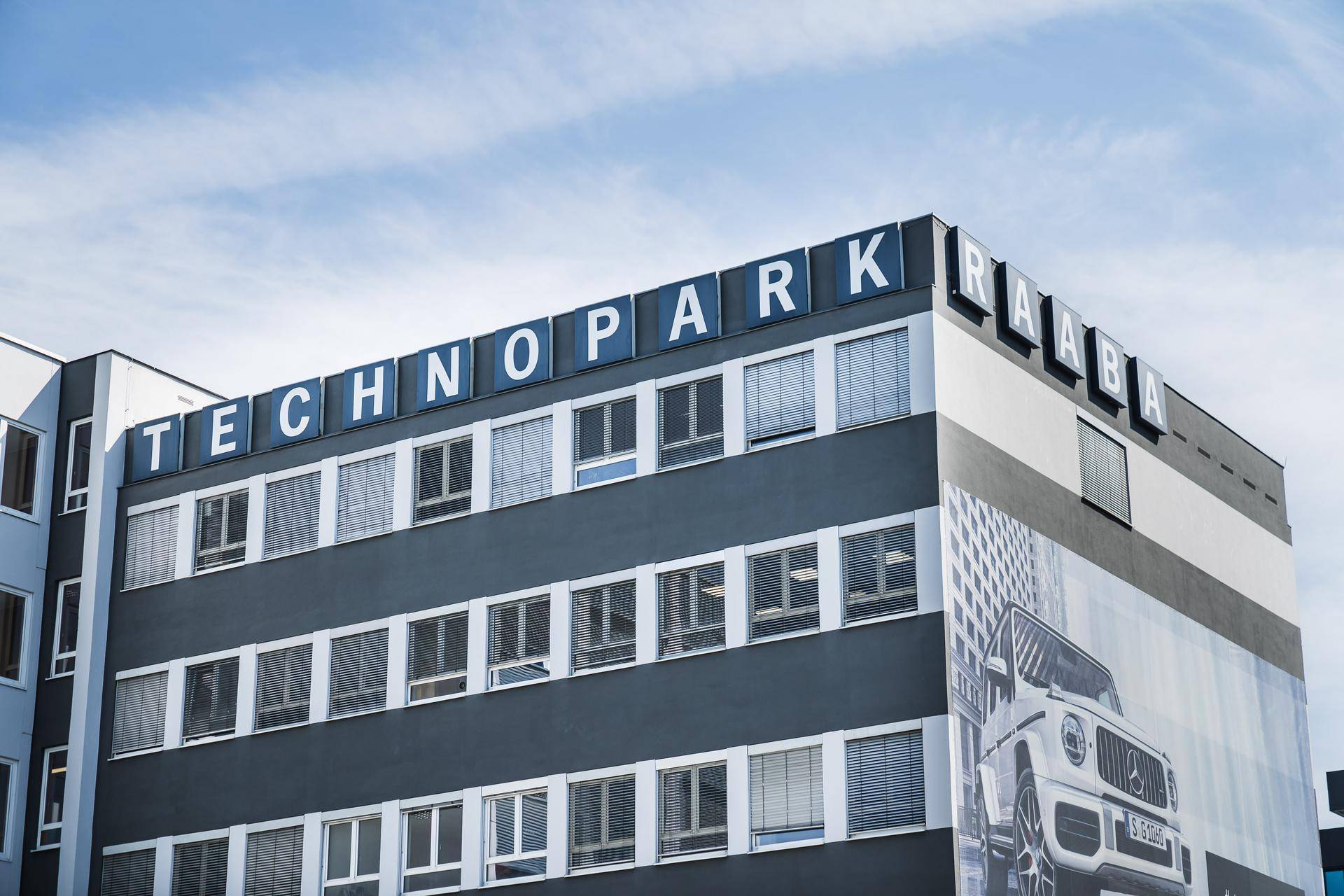 Nahaufnahme der Fassade des Technopark Raaba Gebäudes mit Schriftzug und Werbung.