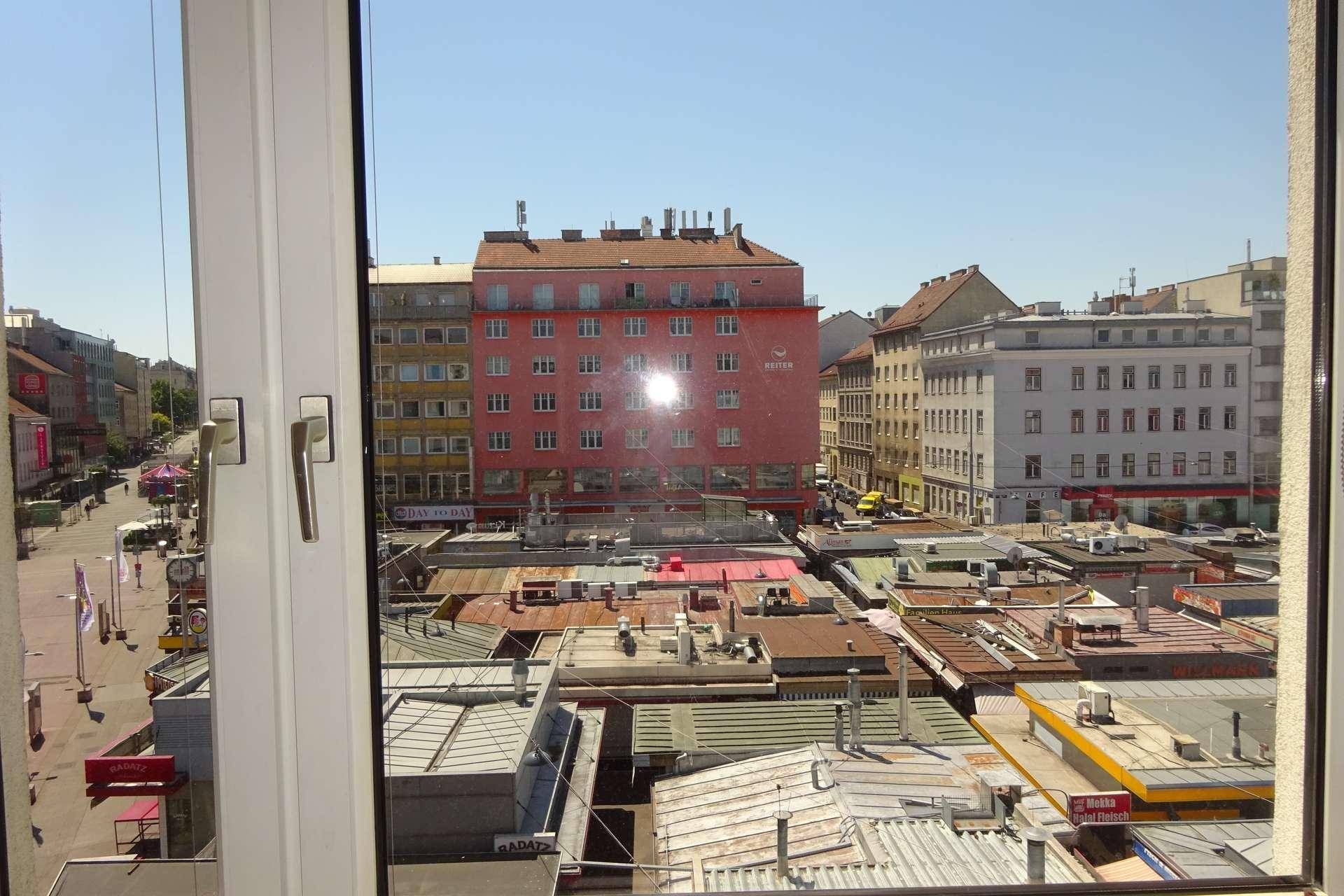 Weitblick über die Dächer der Stadt und belebte Straßen aus einem Fenster.
