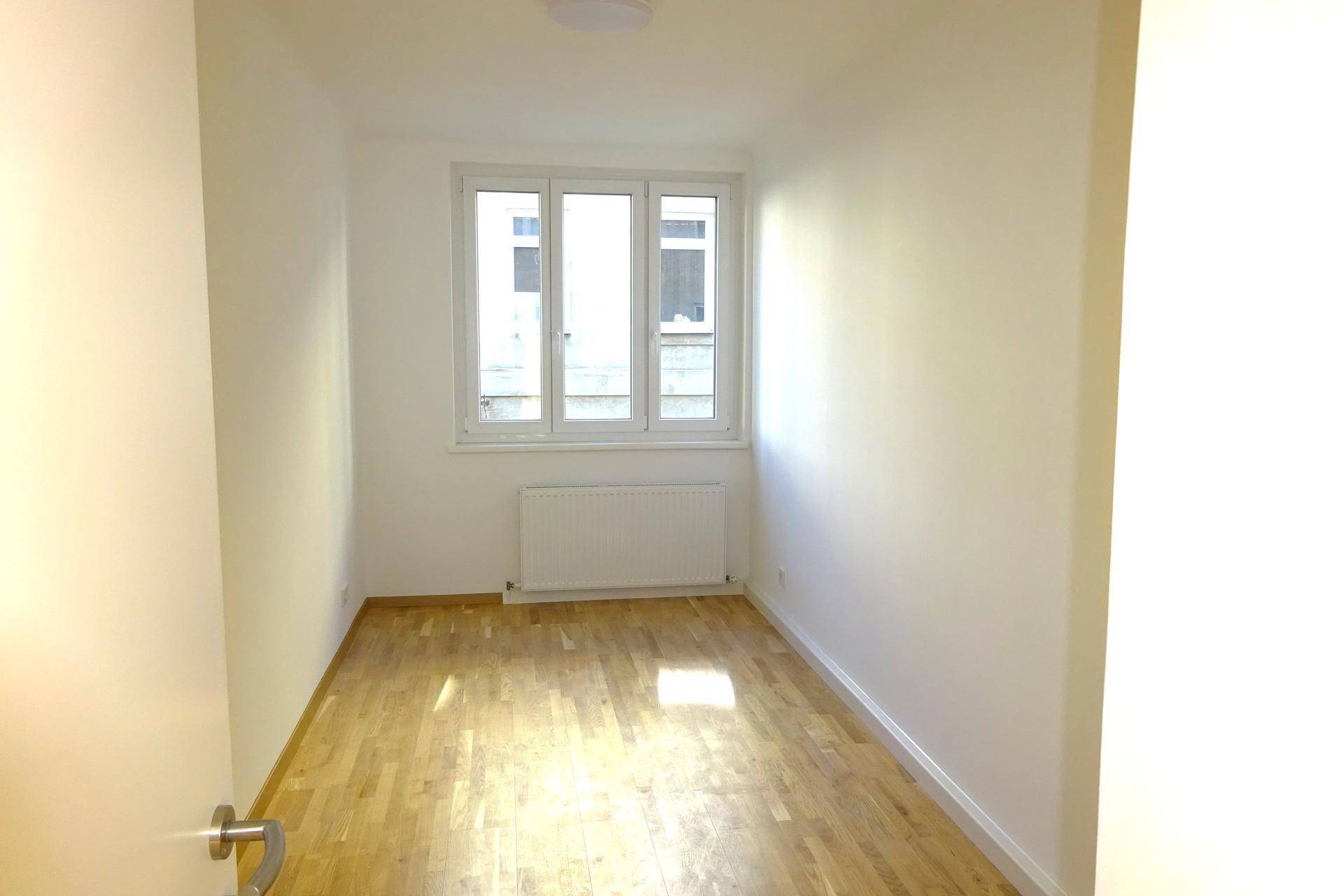 Kleineres Zimmer mit Parkettboden und Fenster, ideal als Schlaf- oder Arbeitszimmer nutzbar.