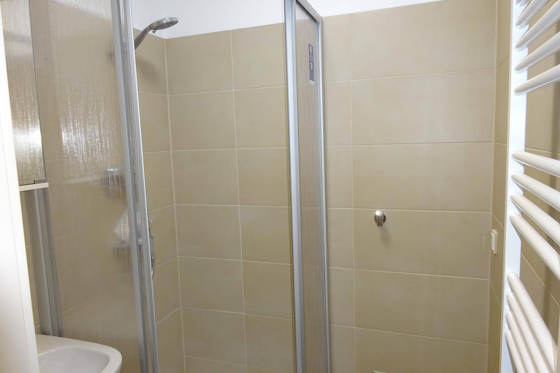 Modernes Badezimmer mit beigefarbenen Fliesen und einer Duschkabine mit Glaswänden.