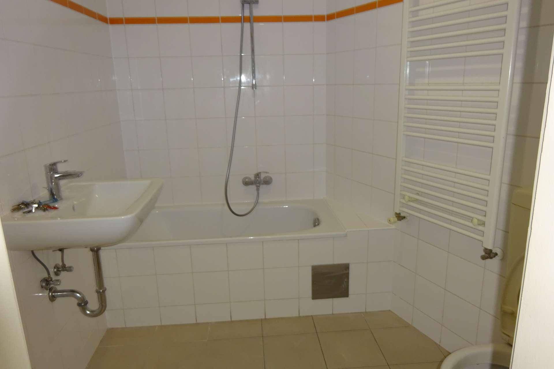 Badezimmer mit Badewanne, Duscharmatur, Waschbecken und einem beheizten Handtuchhalter.
