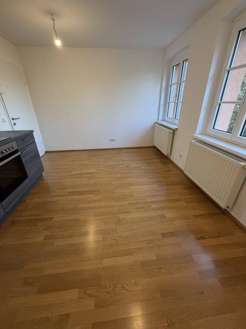 Heller Raum mit Holzfußboden und einem Teil einer modernen Küchenzeile.