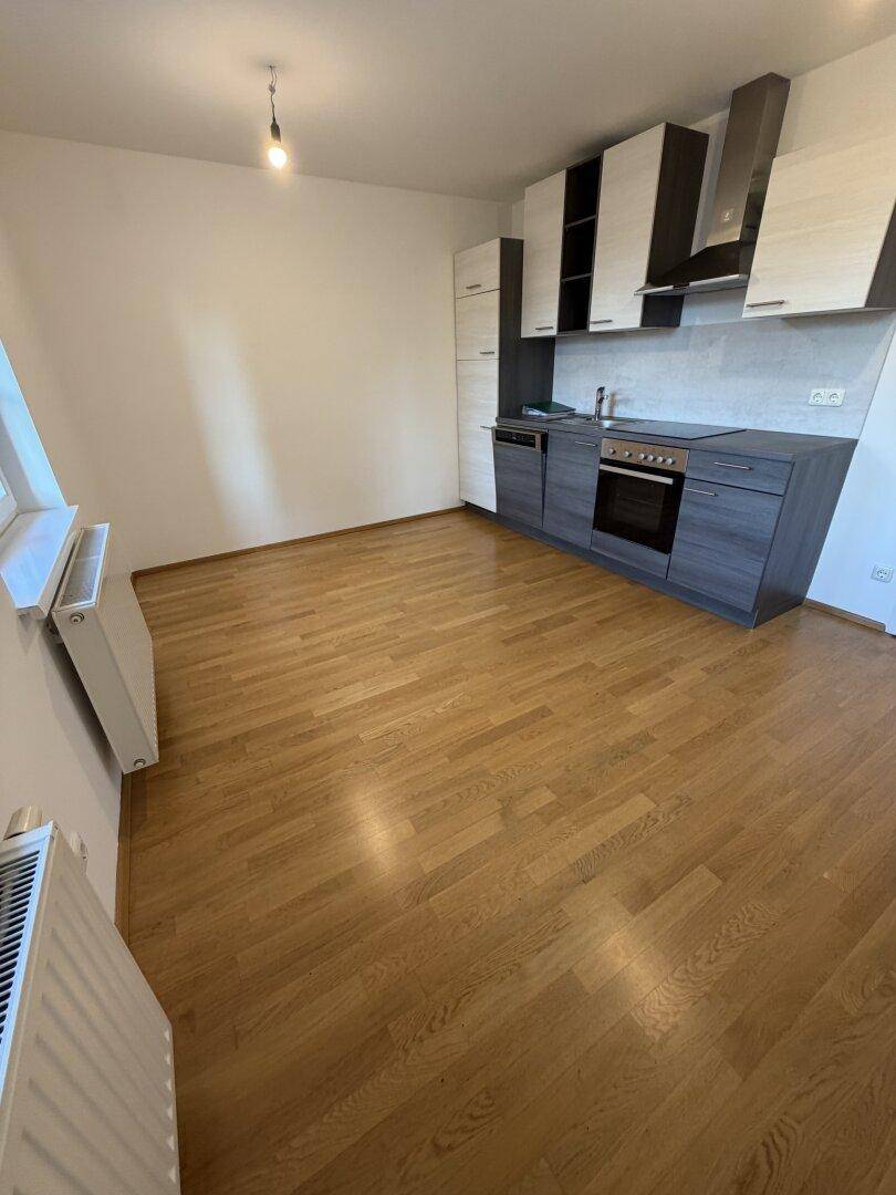 Moderne Einbauküche mit dunklen Unterschränken, hellen Oberschränken und Holzfußboden.
