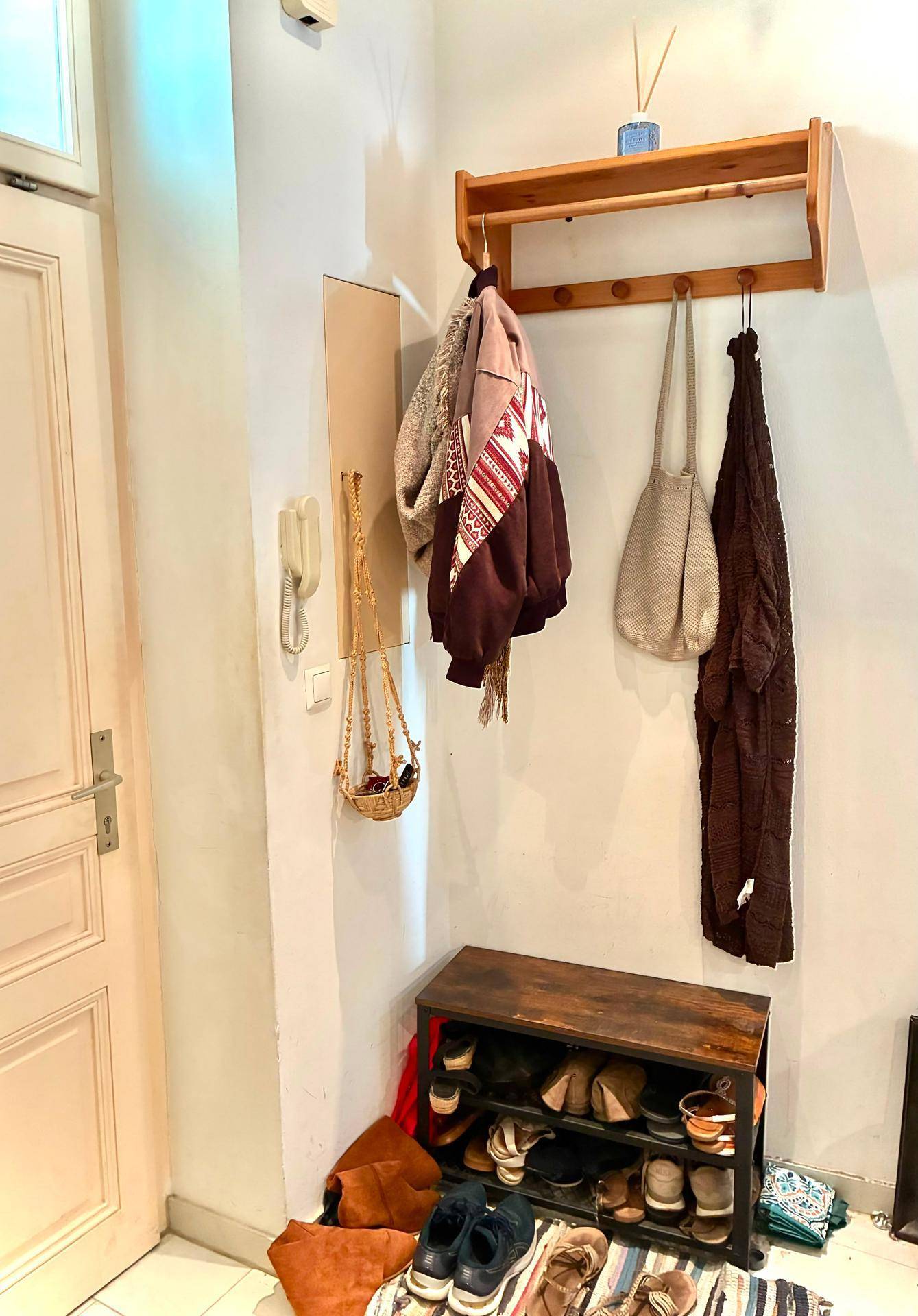 Heller Eingangsbereich mit Garderobe, Schuhregal und einer Tür, die natürliches Licht hereinlässt.