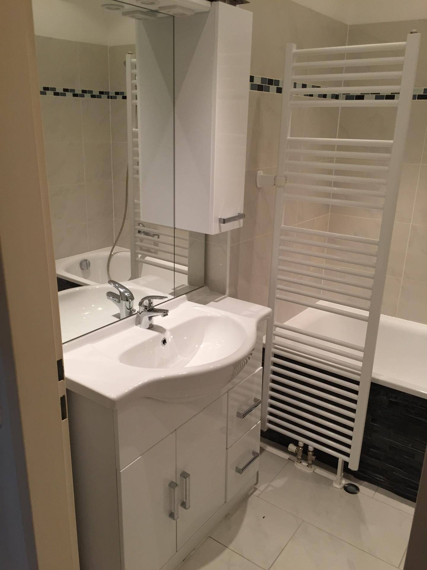 Modernes Badezimmer mit Badewanne, Waschbeckenunterschrank, Spiegelschrank und beheiztem Handtuchhalter.