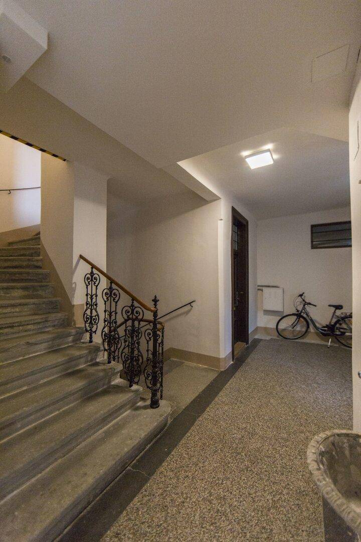 Historisches Treppenhaus mit schmiedeeisernem Geländer und Fahrradabstellmöglichkeit im Eingangsbereich.