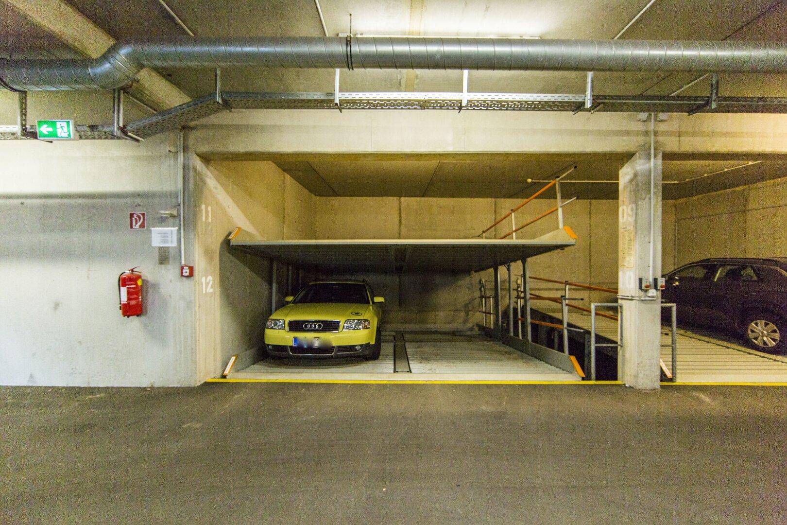Detailansicht eines Duplex-Parksystems in der Tiefgarage mit einem geparkten Fahrzeug.