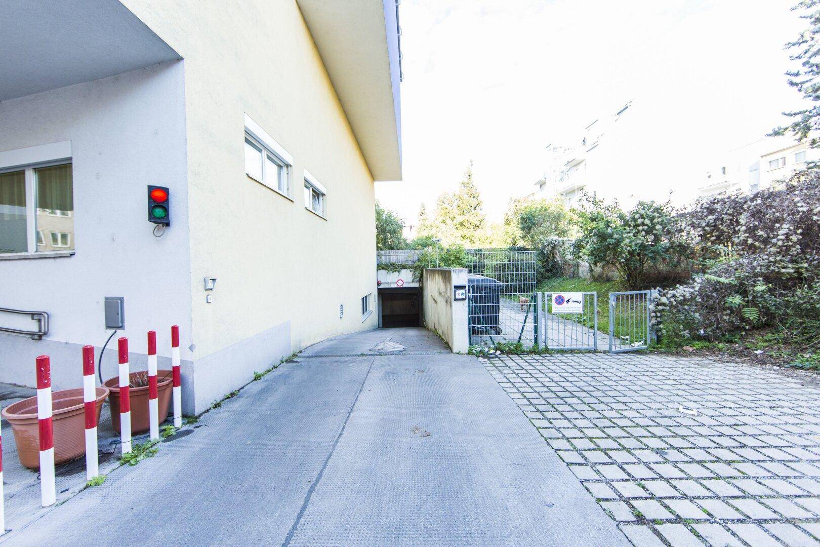 Einfahrt zur Tiefgarage mit Ampel und angrenzendem Grünbereich.