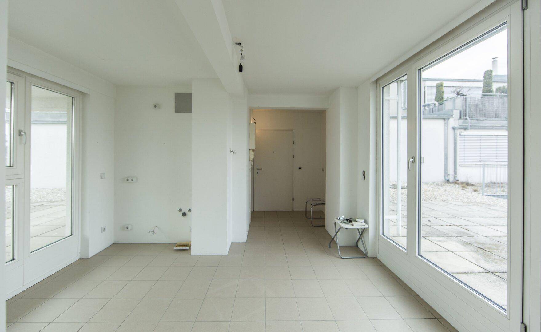 Heller, leerer Raum mit großen Fenstern und Zugang zu einer Terrasse, ideal für individuelle Gestaltung und viel Tageslicht.