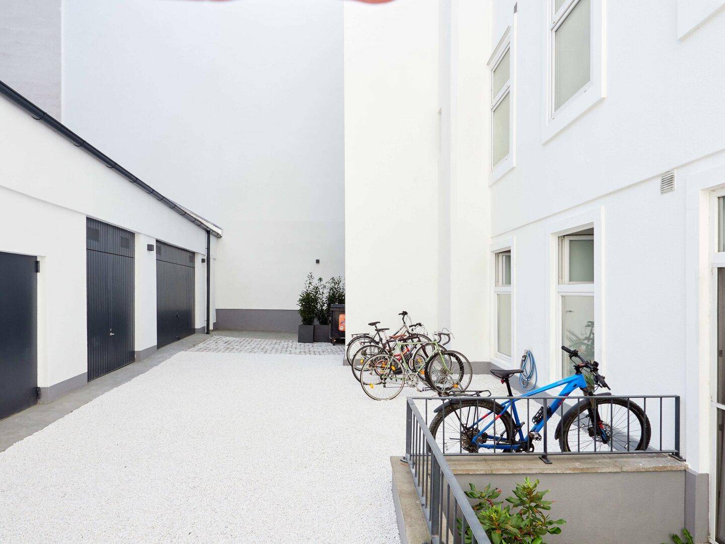 Heller Innenhof mit Fahrradstellplätzen und weißer Gebäudefassade.