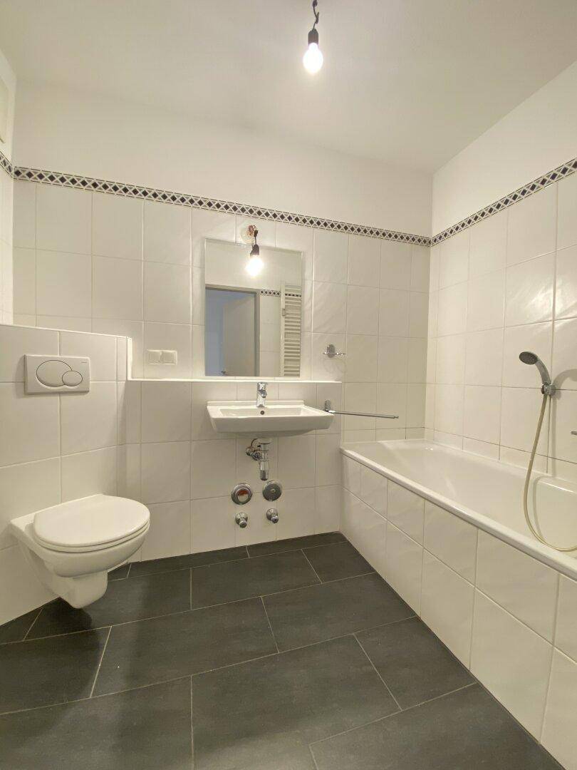 Modernes Badezimmer mit Badewanne, Wand-WC und weißen Fliesen.