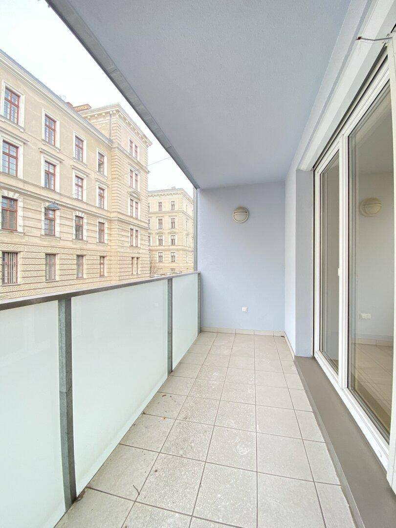Schmaler Balkon mit Fliesenboden und Blick auf die umliegenden Gebäude.