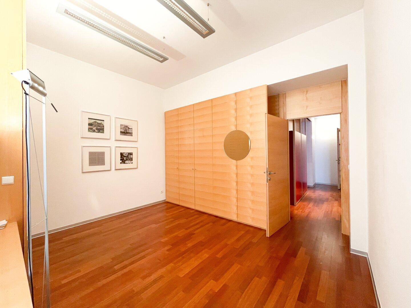 Heller Raum mit Holzboden und einer Wand aus integrierten Schränken, ideal für Stauraum und Organisation.