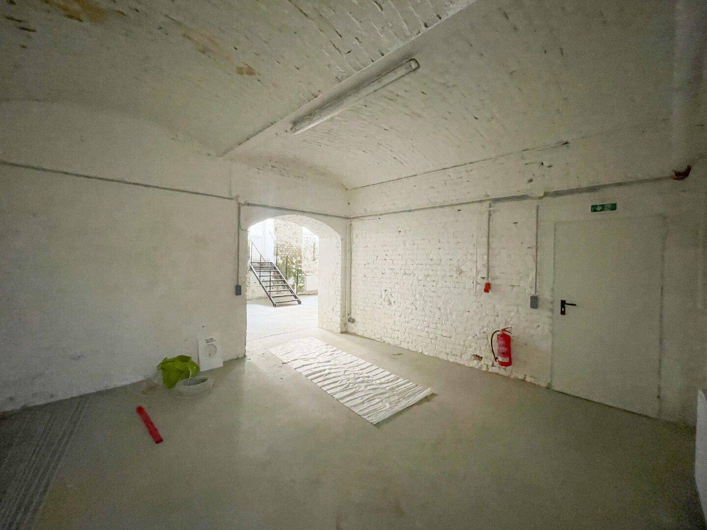 Großer Kellerraum mit weiß getünchten Ziegelwänden, Tonnengewölbe und Zugang zu einem Treppenhaus.