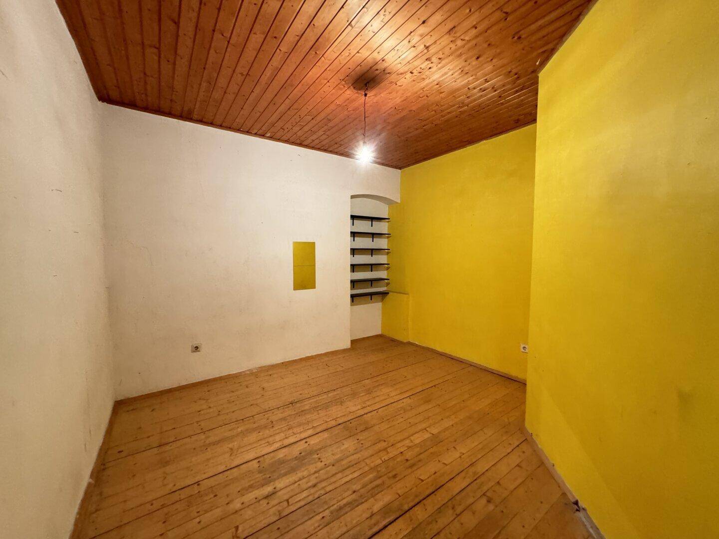 Leerer Raum mit gelben Wänden, Holzdecke und Dielenboden, bereit zur individuellen Gestaltung.
