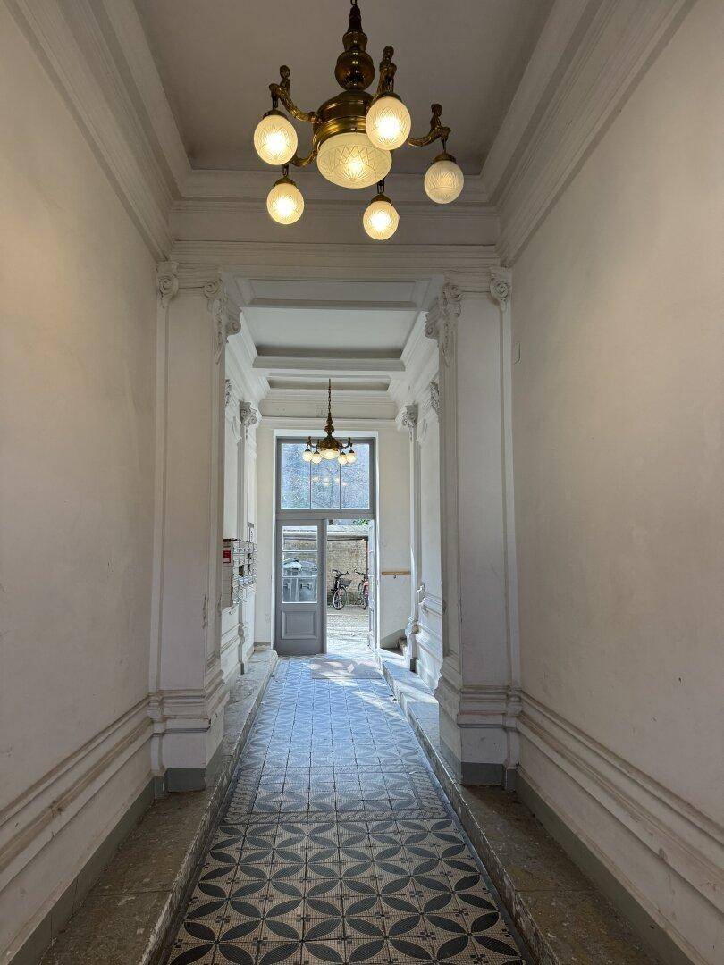 Repräsentative Eingangshalle mit Stuckelementen, gemusterten Fliesen und klassischer Beleuchtung.