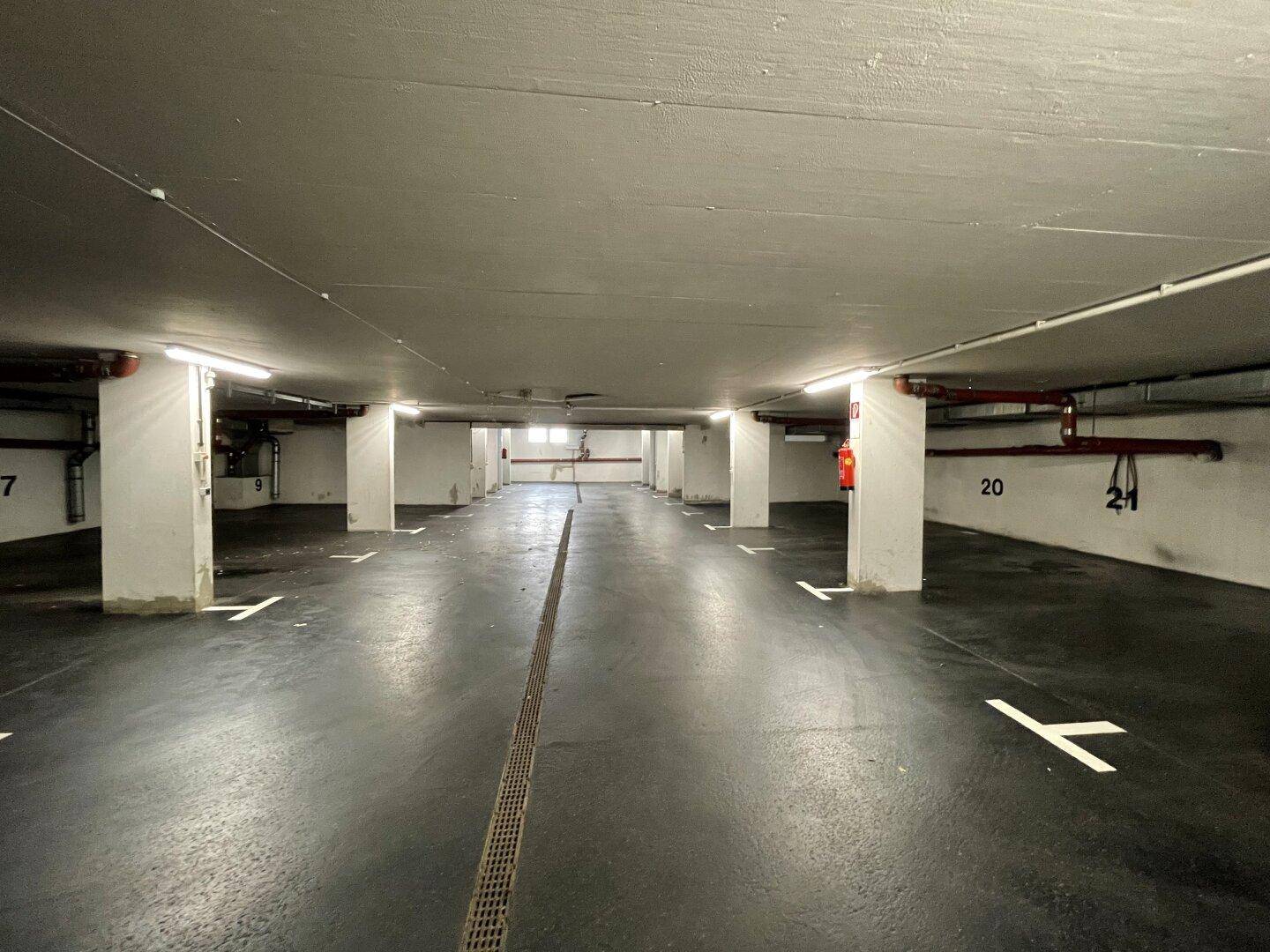 Lange Reihe von nummerierten Stellplätzen in einer sauberen und gut beleuchteten Tiefgarage mit Betonpfeilern.
