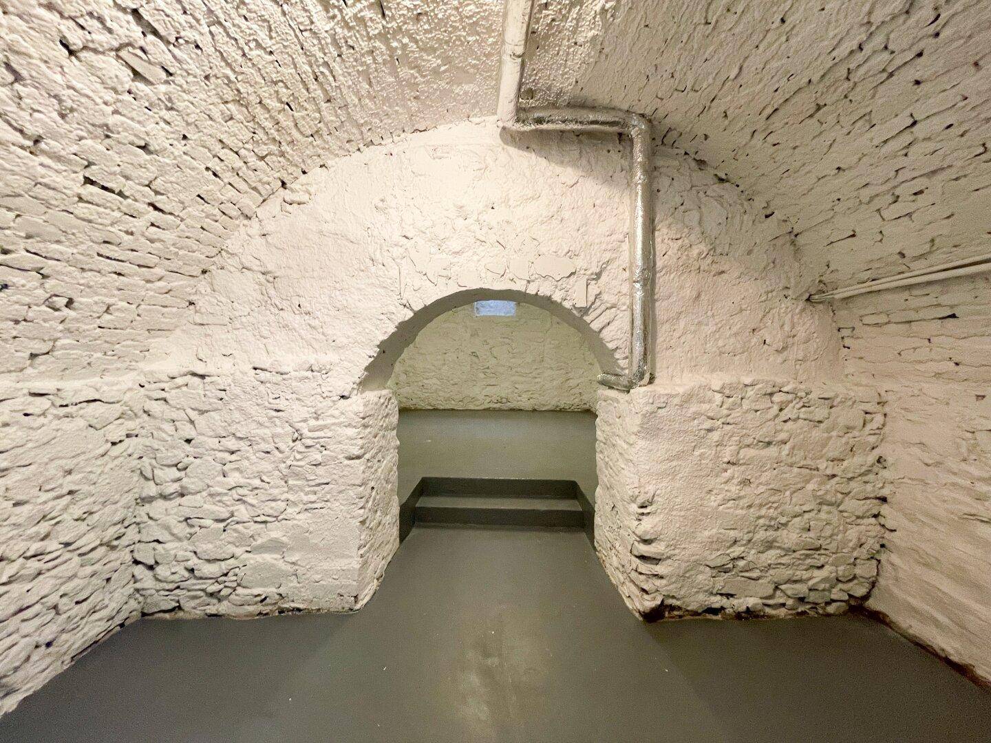 Historischer Gewölbekeller mit weiß getünchten Ziegelwänden und einem robusten Betonboden, ideal als Lagerraum.