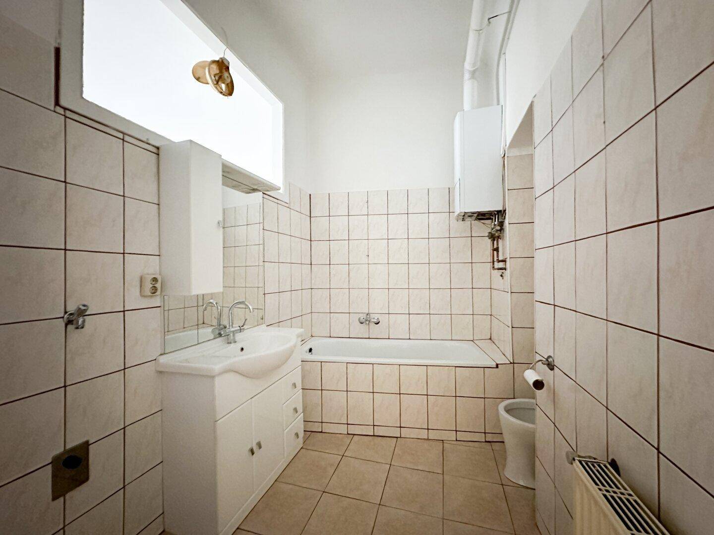 Badezimmer mit Badewanne, Waschbecken und Fliesen in hellem Beige, typisch für die 80er Jahre.