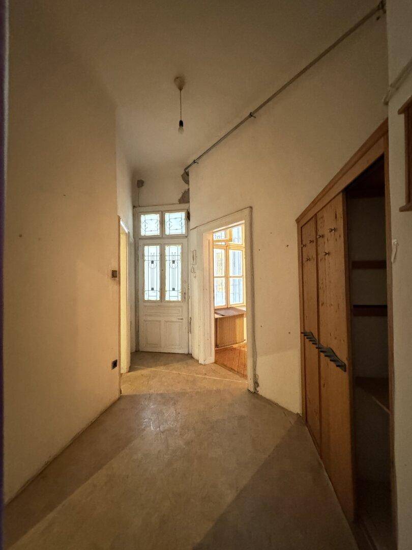 Langer, schmaler Flur mit Holztüren und einem Einbauschrank, der auf weitere Räume führt.