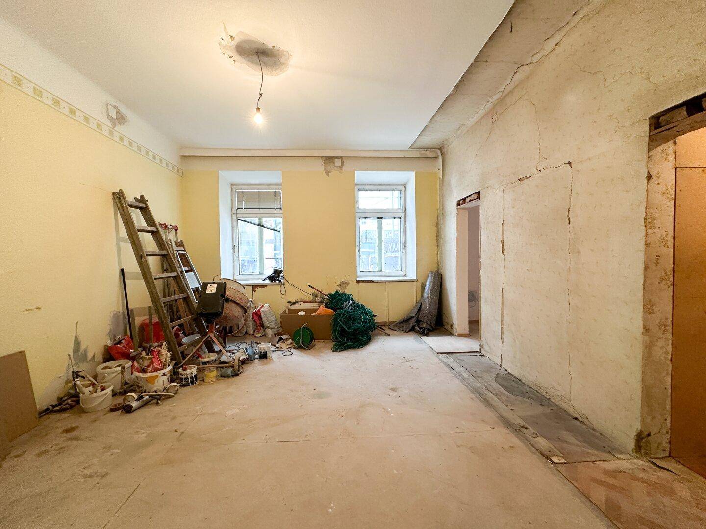 Geräumiger Innenraum in Renovierung mit gelben Wänden und Baustellenmaterialien.