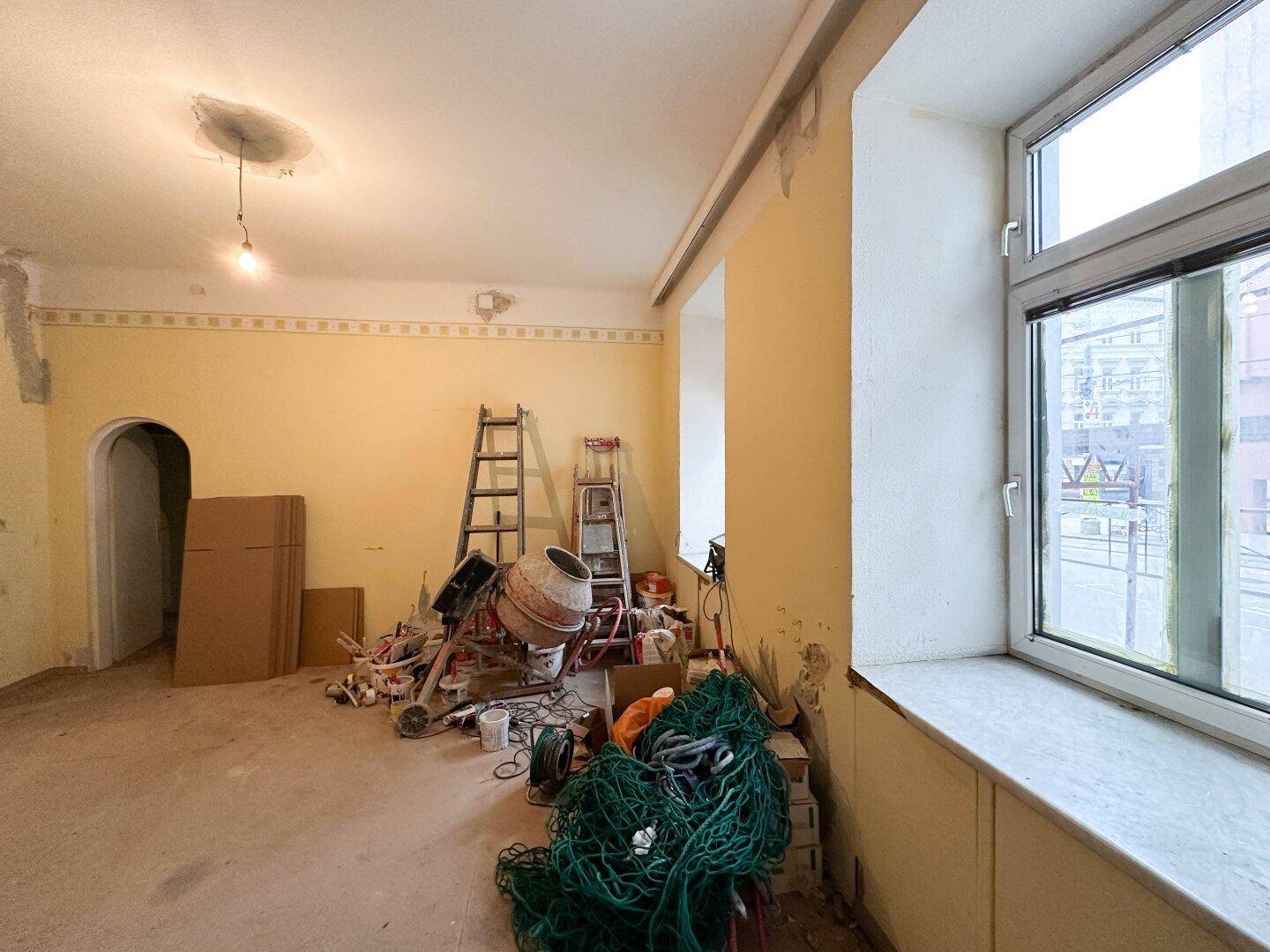 Heller Raum in Renovierung mit Baustellenmaterialien und zwei Fenstern.