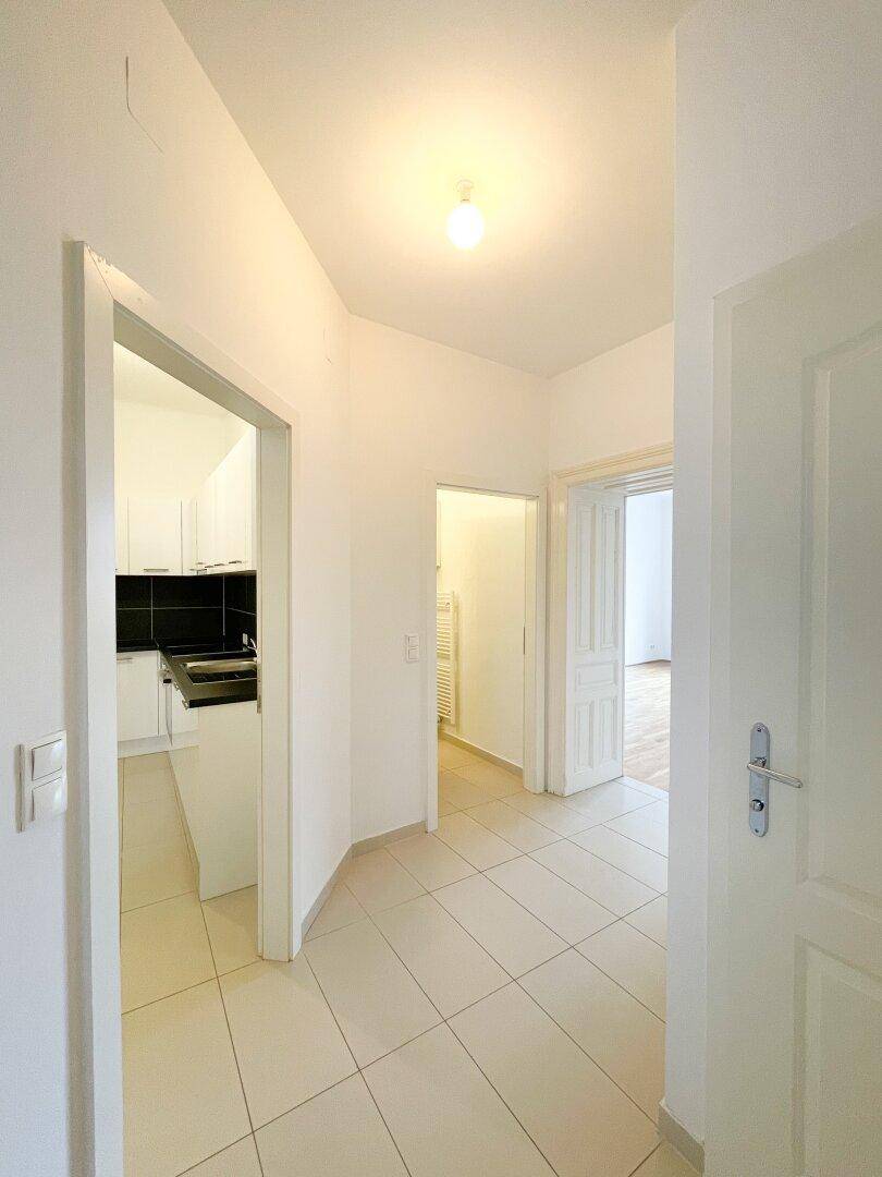 Heller Flur mit Fliesenboden und Zugang zu verschiedenen Zimmern der Wohnung.