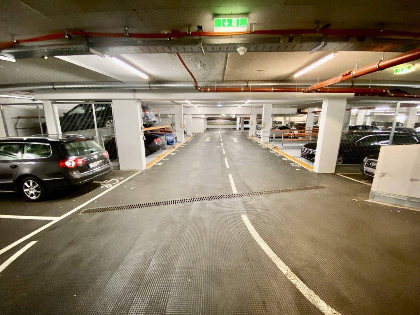 Weitläufige Tiefgarage mit markierten Fahrspuren und vielen Parkplätzen auf mehreren Ebenen.