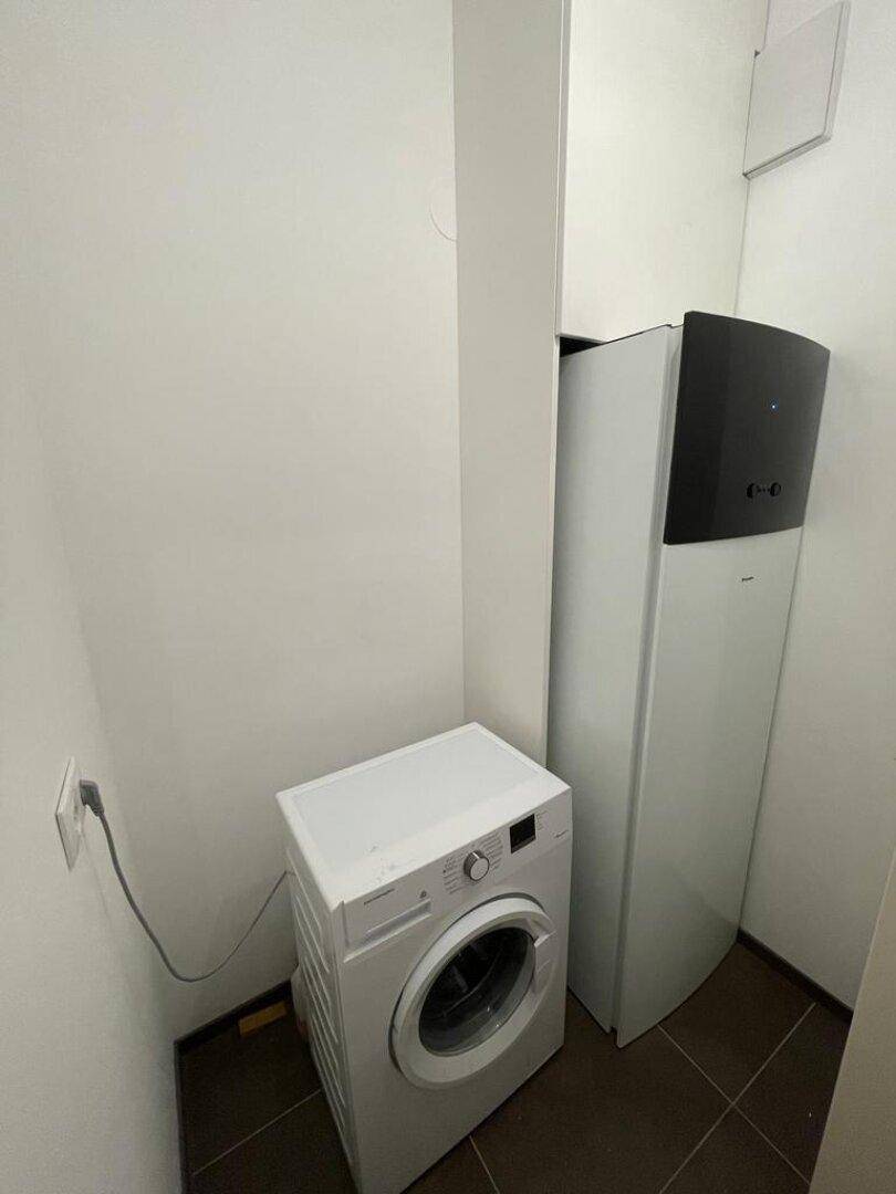 Kleiner Hauswirtschaftsraum mit Waschmaschine und moderner Heizungsanlage.
