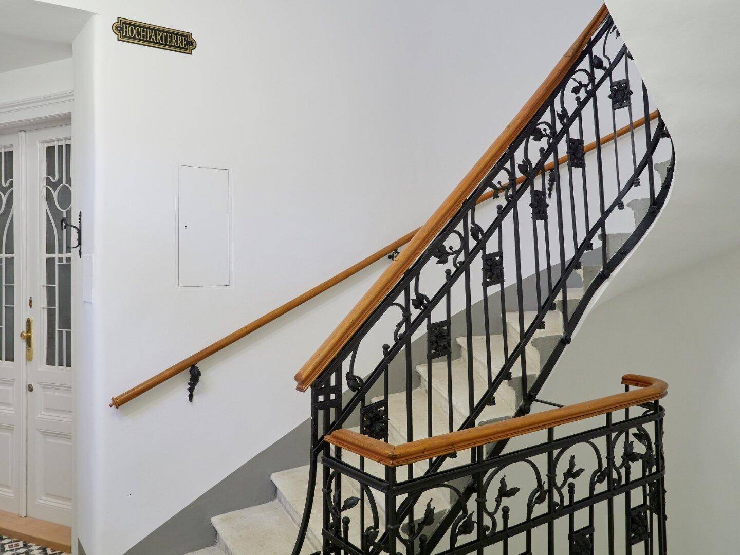 Historisches Treppenhaus mit schmiedeeisernem Geländer und Holzhandlauf.